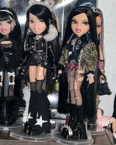 three dolls are dressed up and standing next to each other on a shelf in front of a mirror