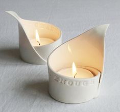 two white tea light holders sitting on top of a table