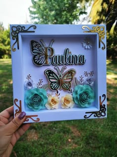 a person holding up a white frame with flowers and butterflies on it