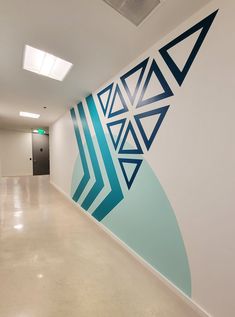 an empty hallway with blue and white designs on the wall