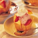 an ice cream sundae with strawberries and whipped cream in a paper wrapper