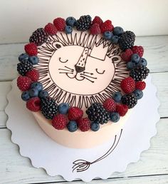 a cake decorated with berries, raspberries and a lion face