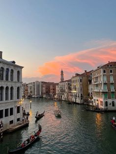 several gondolas on the water in front of some buildings at sunset or dawn