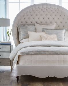 a large white bed sitting in a bedroom next to a window