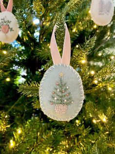 an ornament hanging from a christmas tree decorated with bunny ears and pine cones