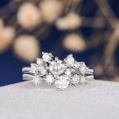 a diamond cluster ring sitting on top of a white cloth