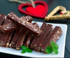 pieces of chocolate on a white plate with mint sprig and heart shaped ornament