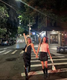 two young women crossing the street at night