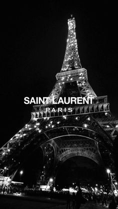 the eiffel tower lit up at night in black and white with text that reads saint laurent paris