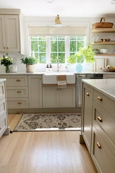 a kitchen with wooden floors and white cabinets, an area rug on the floor that matches the sink