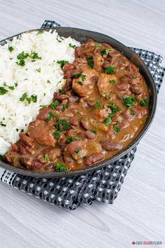 a pan filled with rice and meat covered in gravy on top of a table