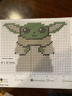 the baby yoda cross stitch pattern is shown on top of a piece of paper