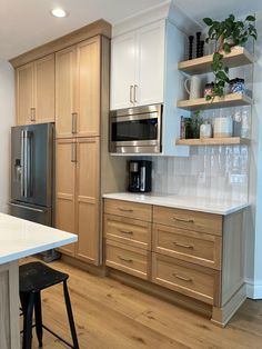 a kitchen with white counter tops and wooden cabinets, along with a stainless steel refrigerator