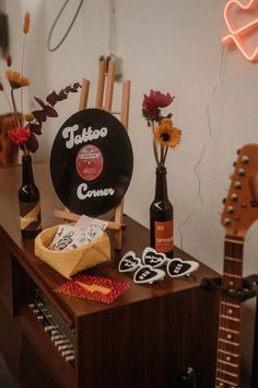 guitars and flowers sit on a table in front of a neon sign