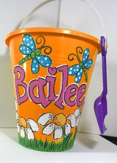 an orange bucket with the word barbiee painted on it and a purple plastic shovel