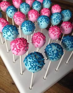 cake pops with blue and pink sprinkles are on a white platter