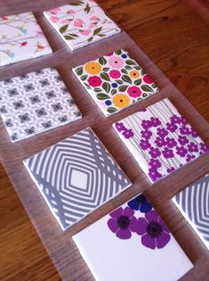 four squares with flowers on them sitting on a wooden table next to papers and scissors