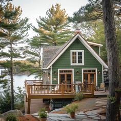 a green house sitting on top of a wooden deck next to a body of water