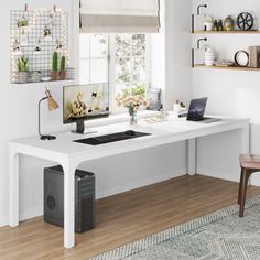 a white desk with a computer on it in front of a window and some shelves