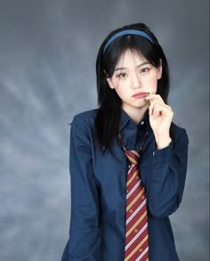 a woman in a blue shirt and tie posing for the camera with her hand on her chin