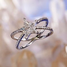 a diamond ring is sitting on top of a flower shaped object in front of a blurry background