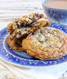 two cookies on a blue and white plate next to a cup of tea