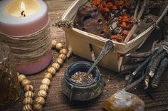 an assortment of candles, beads and other items on a wooden table with glass jars