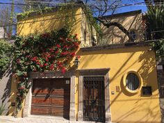 a yellow building with red flowers on the outside and an open garage door in front