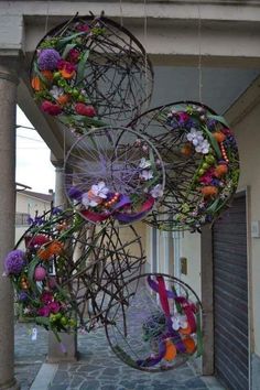 several circular objects hanging from the side of a building with flowers on them and ribbons attached to it