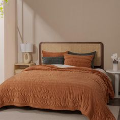 a bed with an orange bedspread and pillows