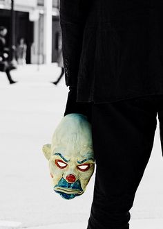 a person with a creepy mask on their hand is holding onto a skateboard in the street