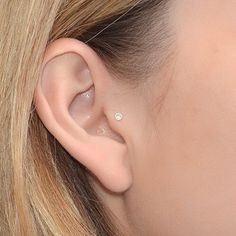 a close up of a person wearing a pair of ear piercings on their ears