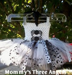 a white and black spider costume hanging on a clothes rack with the words mommy's three angels written below it