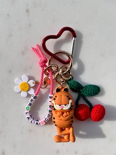 a keychain with a cartoon character on it and two cherries attached to it