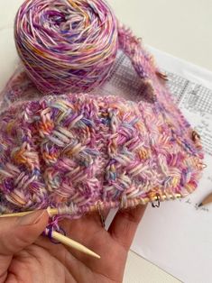 a hand holding a ball of yarn next to a crochet hook