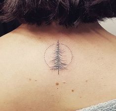 the back of a woman's neck with a pine tree tattoo on it