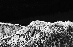 black and white photograph of snow covered mountains at night with stars in the sky above