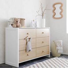 a baby's room with a dresser and teddy bear