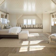 a large bedroom with white walls and wood flooring, along with two windows overlooking the ocean