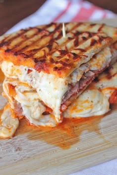 a stack of grilled cheese and meat sandwiches on a cutting board with toothpicks