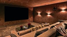 a home theater with two couches and a large screen on the wall behind it