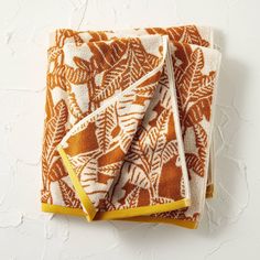 two orange and white towels folded on top of each other with leaves printed on them