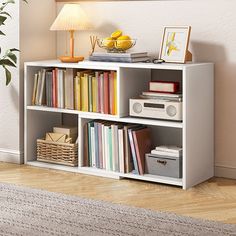 a white book shelf with books and other items on top of it in a living room