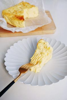 a piece of cheesecake on a paper plate with a gold fork next to it