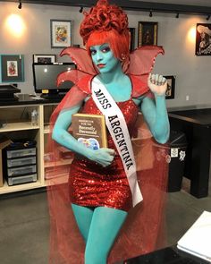 a woman dressed in blue and red is posing for the camera while holding an award