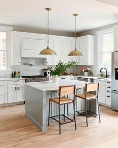 a kitchen with white cabinets and wooden flooring next to an island in the middle