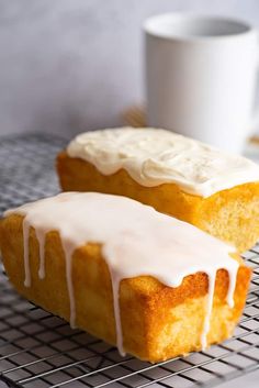 two glazed donuts sitting on top of a cooling rack next to a cup of coffee