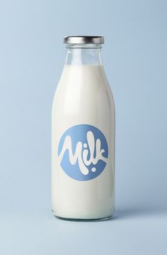 a glass milk bottle with the word milk painted on it's side, sitting in front of a blue background