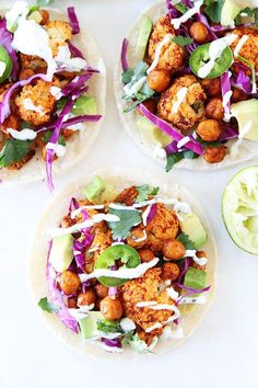 three tacos with chicken, lettuce, and onions on them next to an avocado