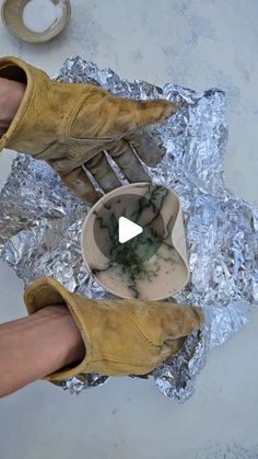 a person standing on tin foil with their feet in the air and holding a bowl